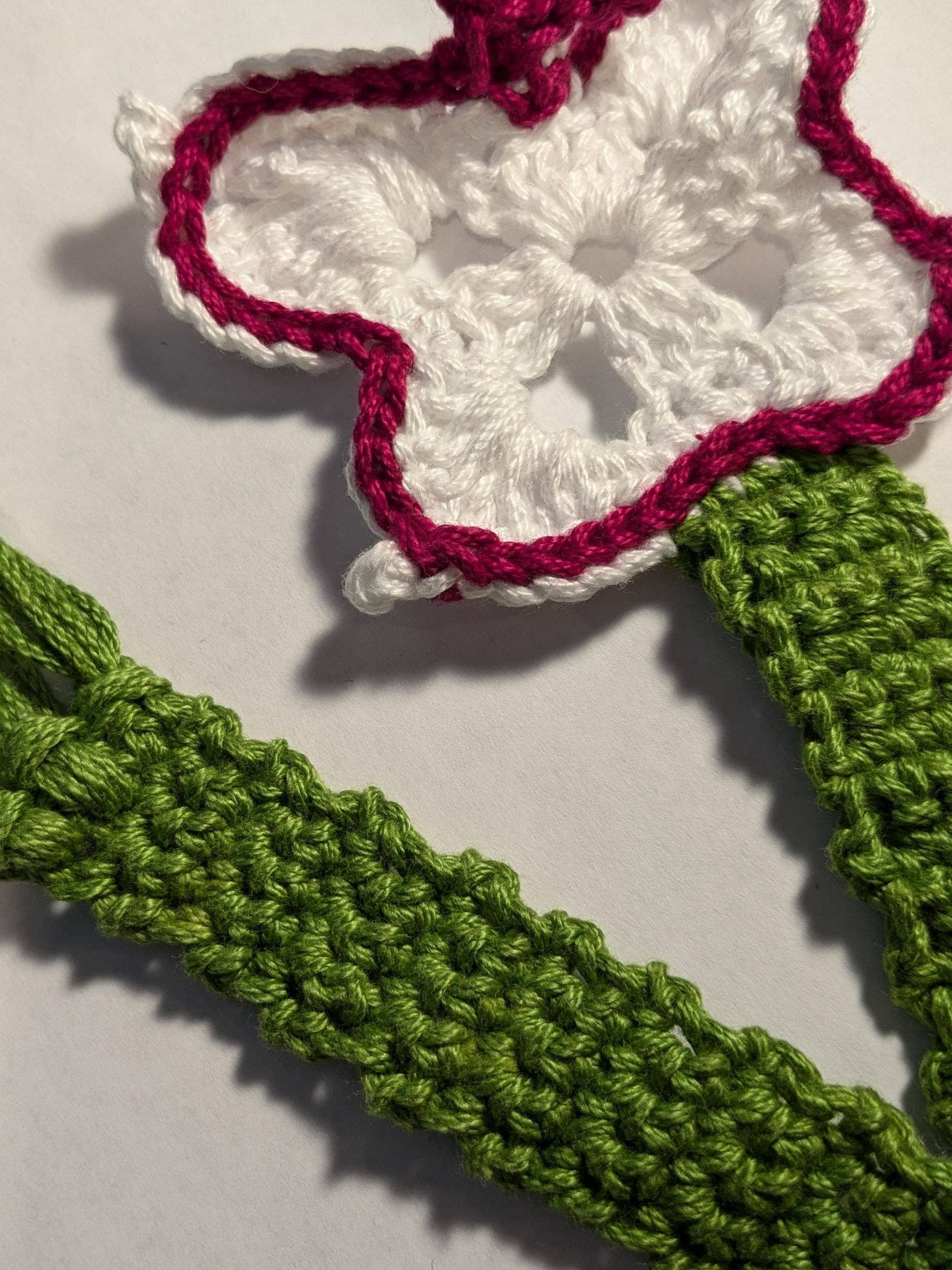 A crochet bookmark in the shape of a  white butterfly with a long tail
